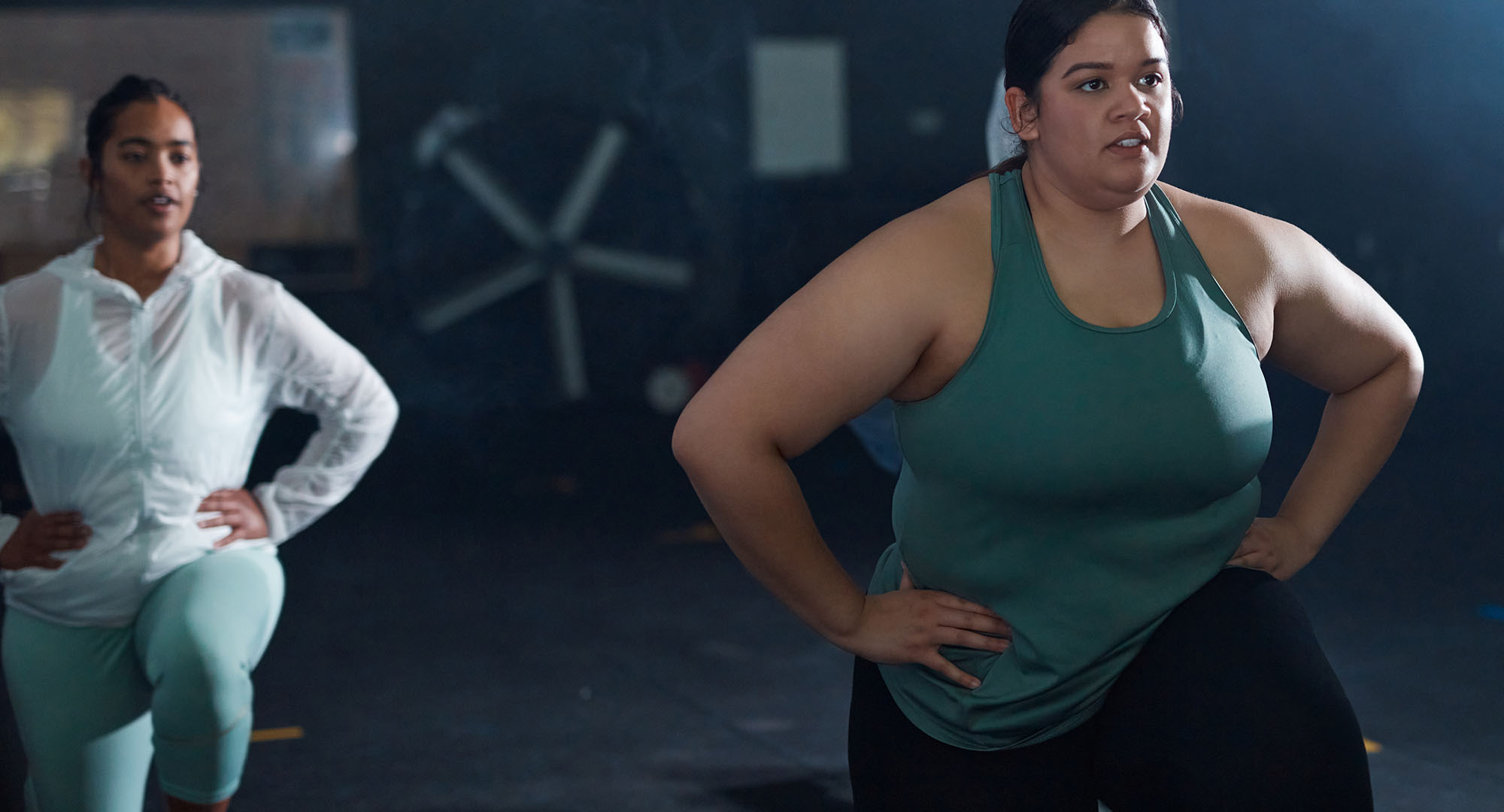 Two women in a gym doing lunges